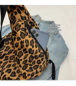 Detail view of the side zipper pocket on a leopard print canvas bag showing phone storage