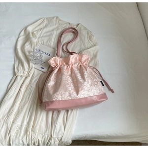 Detail of pink floral drawstring bag with premium silk texture and leather base