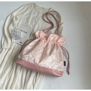 Detail of pink floral jacquard tote bag with drawstring closure on pleated skirt