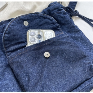 Detailansicht eines dunkelblauen Denim-Rucksacks mit Vordertasche und Metall-Magnetverschluss