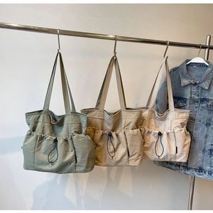 Detailed display of pleated tote bags with adjustable drawstring side pockets in three colors