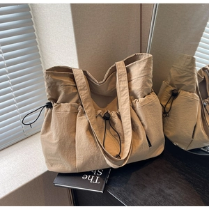 Detail of beige tote bag showing side drawstring pocket and durable nylon texture