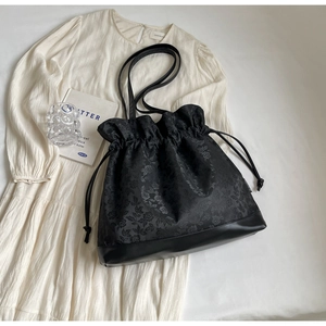 Detail of floral jacquard texture and drawstring closure on black vintage tote bag
