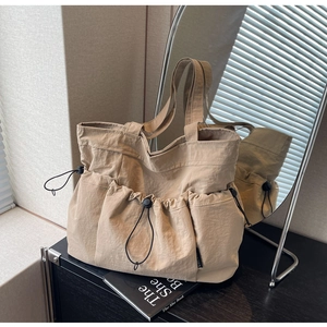 Detail of khaki nylon tote bag with drawstring pockets and minimalist design texture