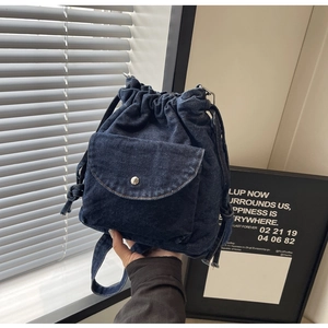 Detail eines dunkelblauen Denim-Kordelzug-Rucksacks mit silberner Metalldruckknopftasche