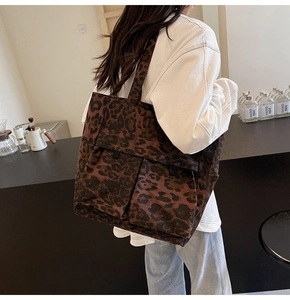 Detailansicht der großen Canvas-Tragetasche mit Leopardenmuster und Fronttaschen am Modell