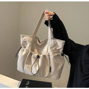 Detail of pleated beige tote bag with drawstring pockets and lightweight nylon texture