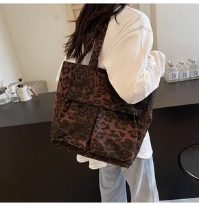 Seitenansicht der Canvas-Einkaufstasche mit Leopardenmuster und Taschen am Modell
