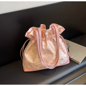 Detail of pink floral jacquard satin drawstring bag on black leather background