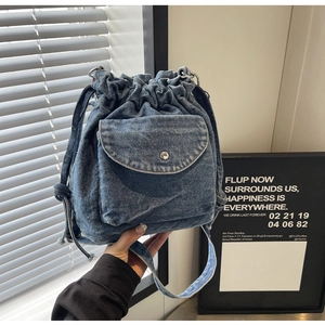 Detailaufnahme der blauen Denim-Beuteltasche mit Kordelzug und vorderer Klappentasche