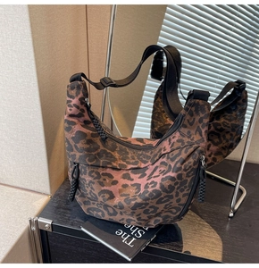 Detailed close-up of leopard print canvas crescent bag with black adjustable strap