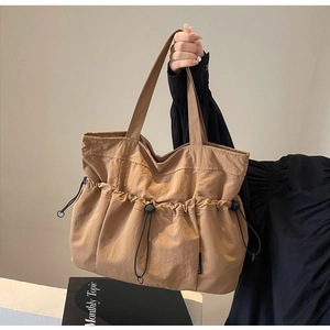 Detail of khaki pleated tote bag featuring a drawstring front pocket and durable nylon texture