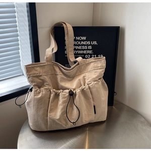 Detail of minimalist beige tote bag with pleated nylon fabric and drawstring pockets