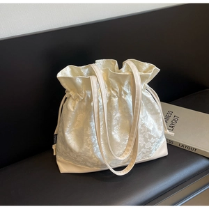 Detail of cream drawstring tote bag with floral jacquard texture and leather bottom