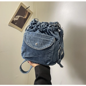 Detailansicht eines dunkelblauen Denim-Rucksacks mit silbernen Ringen und Klappentasche
