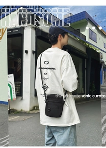 Street style black nylon crossbody bag worn by a male model in a modern urban setting