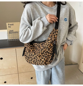 Detailed view of leopard print canvas crossbody bag with black adjustable strap and zipper