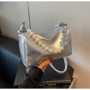 Détail du sac argenté avec perles blanches et poignées en chaîne métallique en forme de cœur