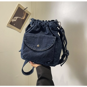 Detail der dunkelblauen Denim-Beuteltasche mit silberner Schnallentasche und verstellbarem Gurt