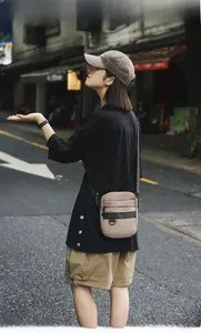 Outdoor shot of khaki crossbody bag with multi-compartments and adjustable strap