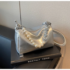Détail du sac à main argenté avec bandoulière en perles et chaîne à motifs cœurs