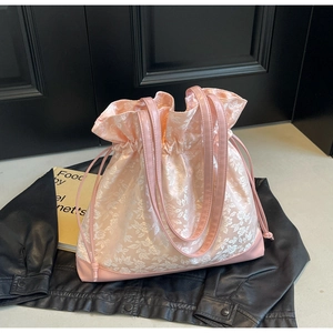 Detail of pink floral satin drawstring bucket bag with leather base and handles