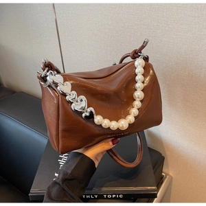 Détail du sac à main marron en cuir plissé avec perles et chaîne de cœur argentée