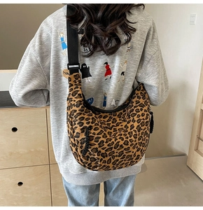 Detail of leopard print canvas crescent bag showing the adjustable wide strap on model