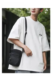 Detail of black crossbody bag with adjustable strap and multiple zip pockets shown on model