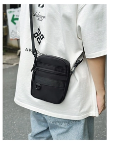 Outdoor street style shot of a black nylon crossbody bag with adjustable strap and D-ring
