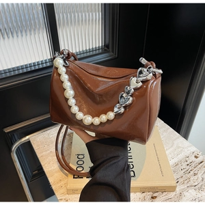 Détail du sac cylindrique marron foncé avec chaîne de perles et cœurs argentés