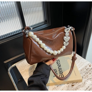 Vue détaillée du sac à main en cuir verni marron avec perles et breloque en cœur argenté