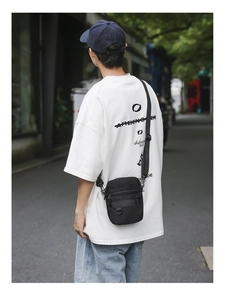 Outdoor shot showing back view of man wearing black multi-pocket crossbody bag