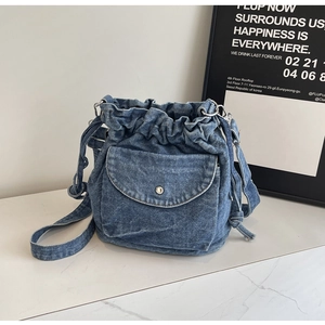 Detail der blauen Denim-Beuteltasche mit Kordelzug und vorderer Klappentasche Design