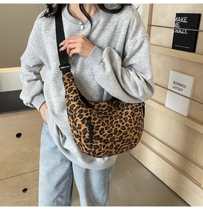 Close-up of leopard print canvas crescent bag with black adjustable strap and metal hardware