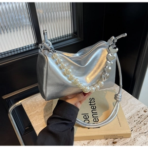 Détail d'un sac à main argenté métallisé avec chaîne en perles et breloques en cœur
