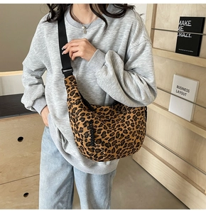 Detail of leopard print crescent bag with adjustable black shoulder strap in casual setting