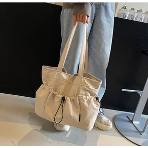 Detailed shot of oversized pleated tote bag with side drawstring pockets and logo label