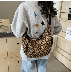 Detail view of leopard print crescent bag with black adjustable shoulder strap