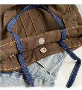 Close-up of brown canvas tote with denim strap and silver magnetic metal buckle closure