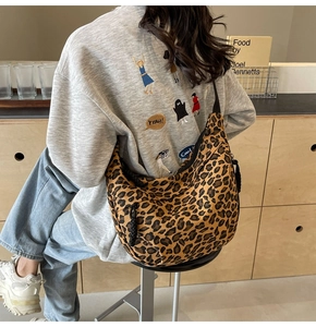 Detail view of leopard print canvas crescent bag with black strap and metal zipper detail