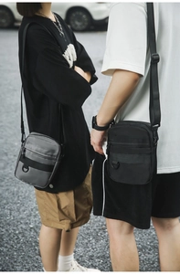 Detail view of grey and black nylon crossbody bags with utility D-ring and zipper pocket