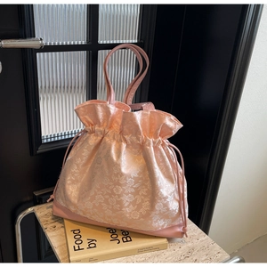 Close-up of pink floral jacquard drawstring bag with smooth texture and leather base