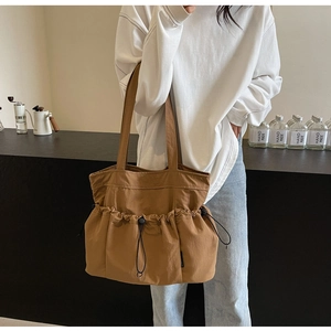 Brown pleated tote bag with drawstring pockets shown in a casual lifestyle setting