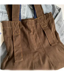Detailed close-up of heavy brown canvas bag fabric texture and wide shoulder strap stitching