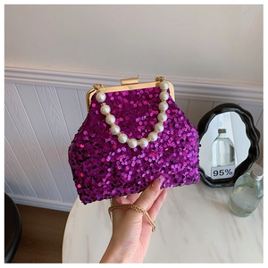 Makroaufnahme einer lila Pailletten-Abendtasche mit Perlengriff und goldener Kette