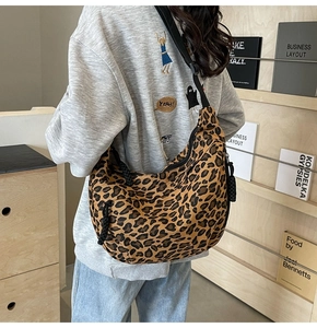 Close-up of leopard print canvas crescent bag with black strap worn by a model