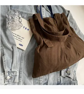Detail view of a vintage dark brown canvas tote bag resting on denim with decor