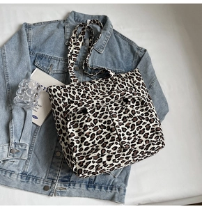 Detail der Leoparden-Leinentasche mit Vordertaschen auf Denim-Jacken-Hintergrund