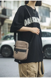 Close-up of a khaki nylon crossbody bag with multi-pocket design on a male model